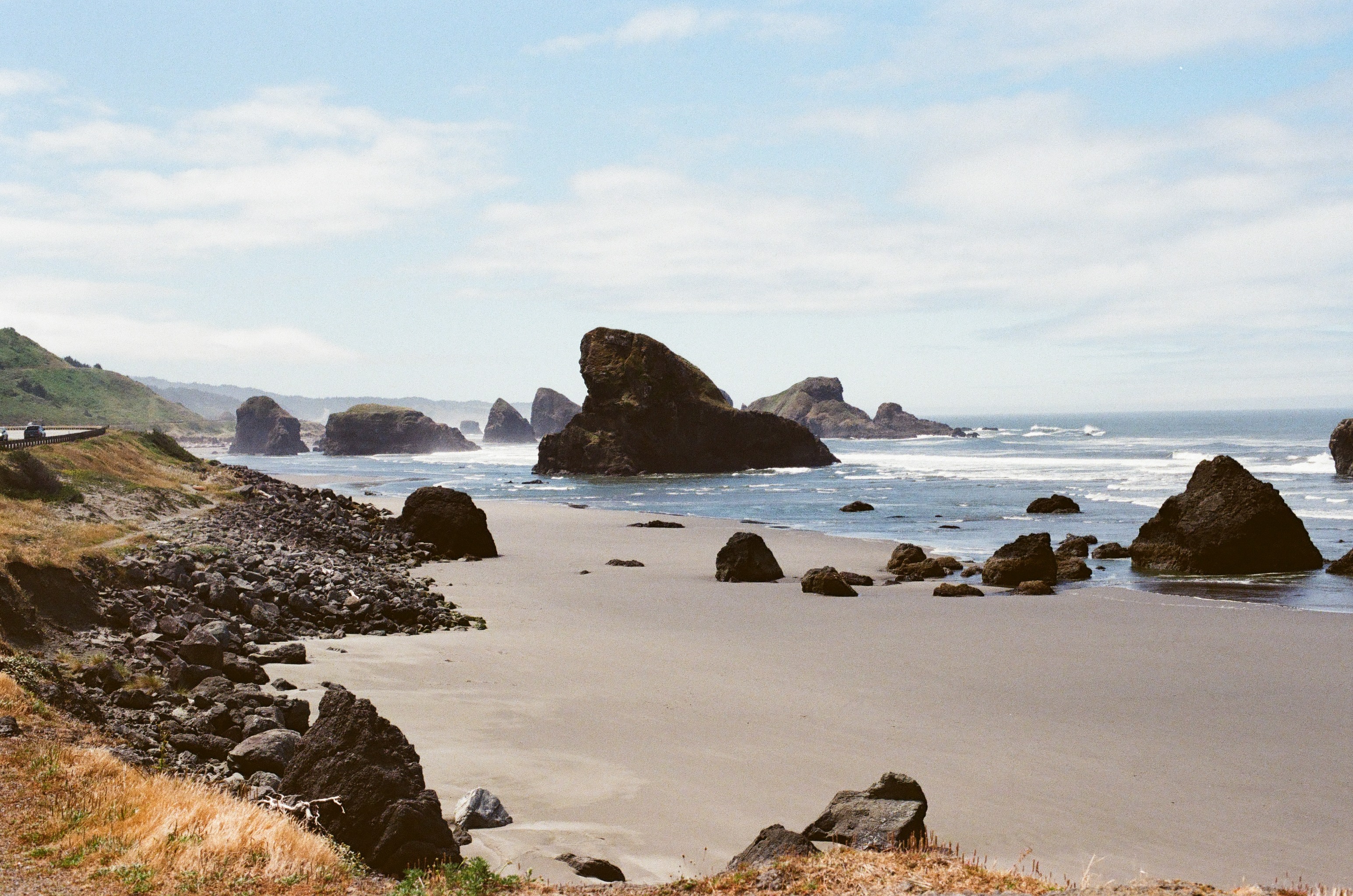 Dark rock formations and open beach along the Oregon Coast.