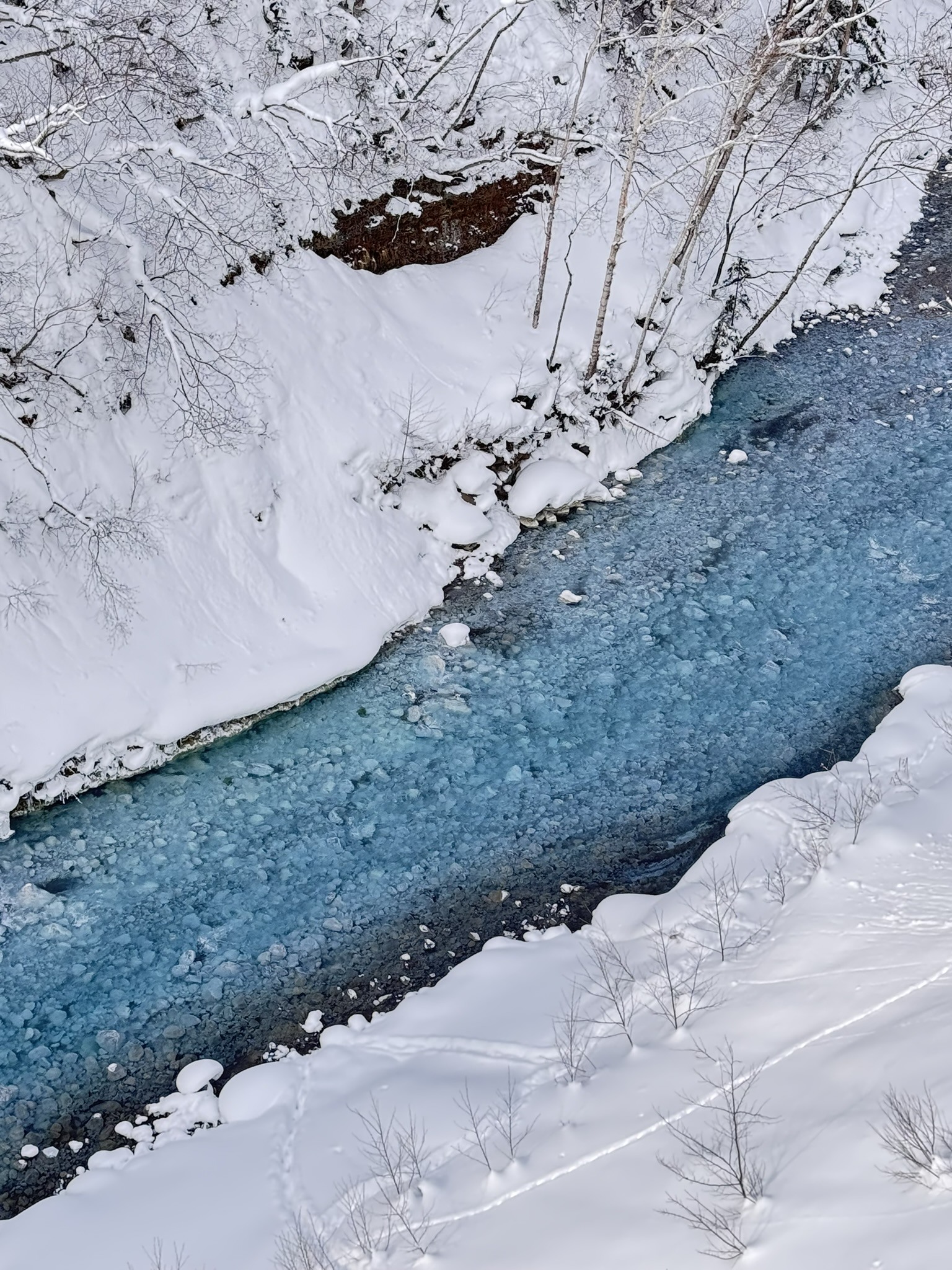 A narrow icy channel cutting through snow in Japan.