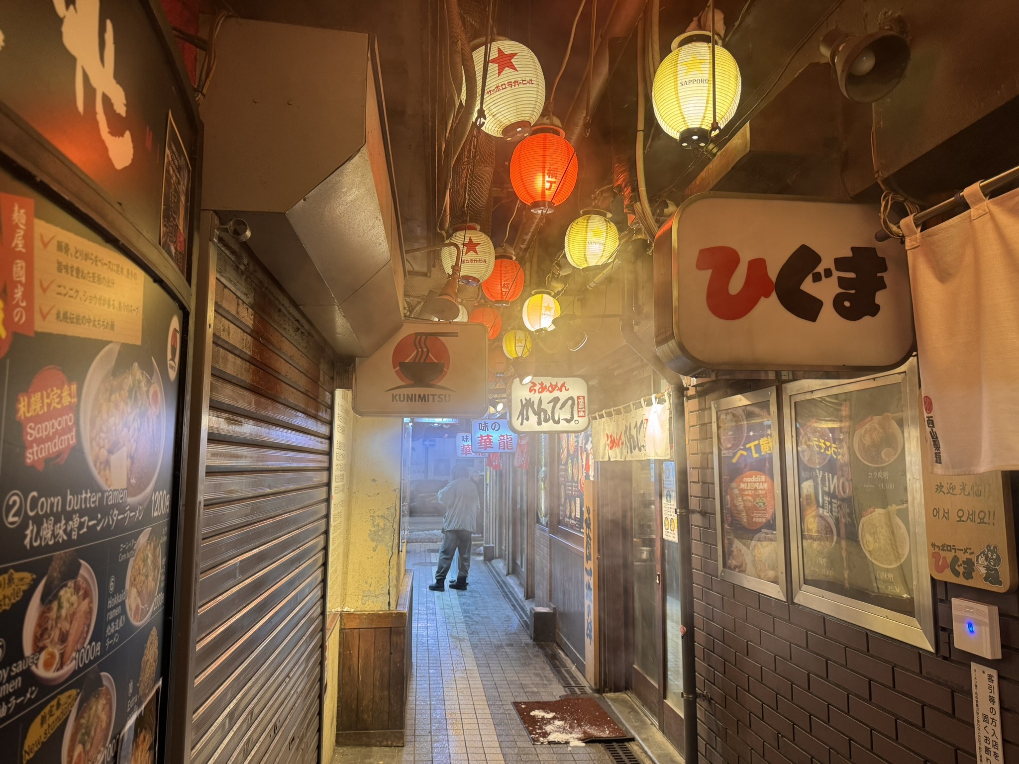 Narrow Japanese passage lit by warm lanterns and storefront glow.